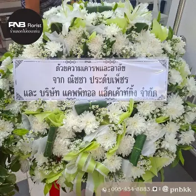 ภาพส่งจริง พวงหรีดดอกไม้สด โทนสีขาว-เขียว จัดด้วยเบญจมาศขาว ลิลลี่ขาว และดอกไม้ขาวแซม ประดับใบตองม้วนและโบว์ริบบิ้นเขียว ณ อ.เมืองขอนแก่น จ.ขอนแก่น